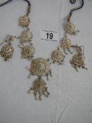 A white metal necklace and earrings, complete and in good condition.