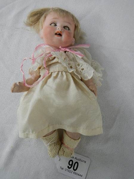 An early 20th century bisque headed doll, 19.5 cm.