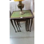 A dark wood nest of tables with green leather inset tops.