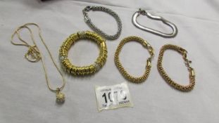 3 gold coloured bracelets, 2 silver coloured bracelets and a gold coloured pendant.