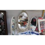 An ornate triple dressing table mirror in white with gilded features,