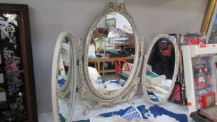 An ornate triple dressing table mirror in white with gilded features,