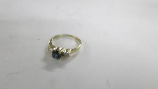 A diamond and sapphire three stone ring in a gold band, size N.