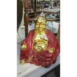 A large gilded pottery figure of Buddha in red robes.