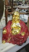 A large gilded pottery figure of Buddha in red robes.