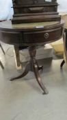 A dark wood stained drum table with 3 drawers and gilt decorated green leather top, height 60 cm,