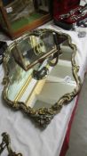 A gilt and silver coloured surround mirror with floral detail.