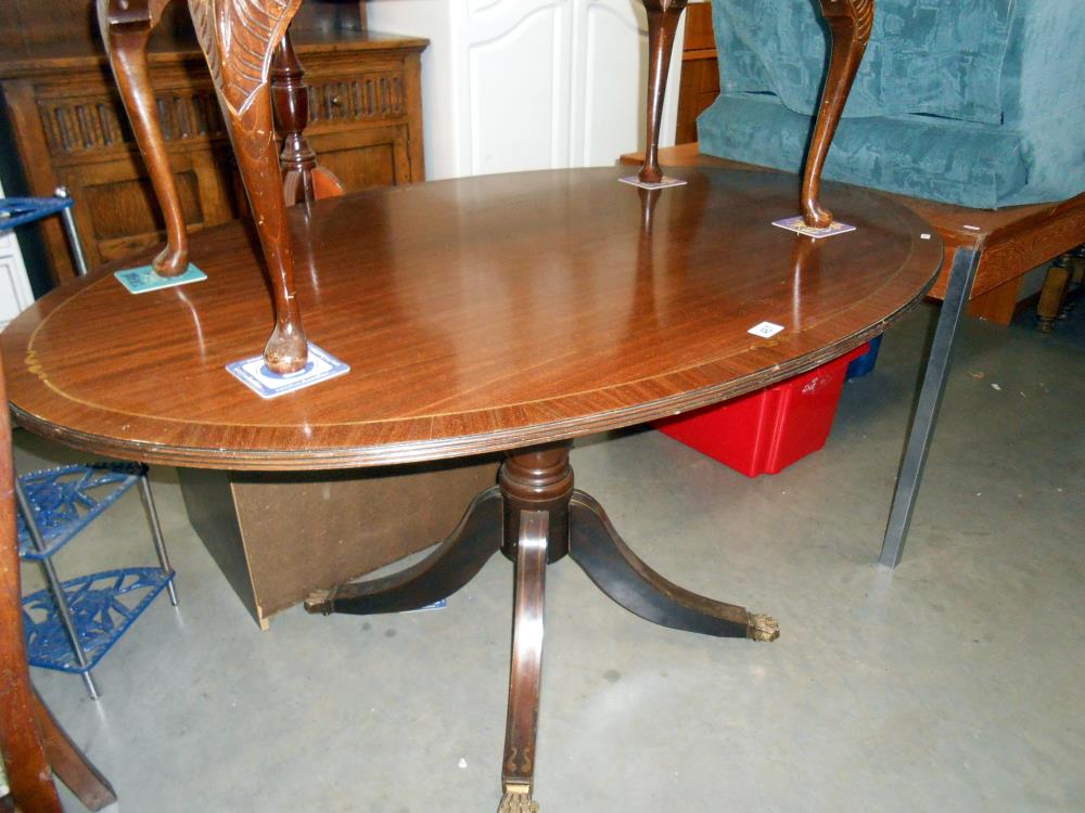 A darkwood stained oval dining table with brass string inlay on centre column, Height 74.