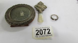 A small antique silver photo frame, a silver babies rattle a/f and an silver ring.