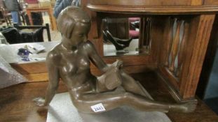 An Austrian art deco female nude figure reading, a/f (repair to ankle).