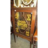 An oak cabinet with sign written glass door.