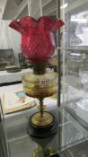 A Victorian oil lamp with brass column, glass font and complete with burner, shade and chimney.