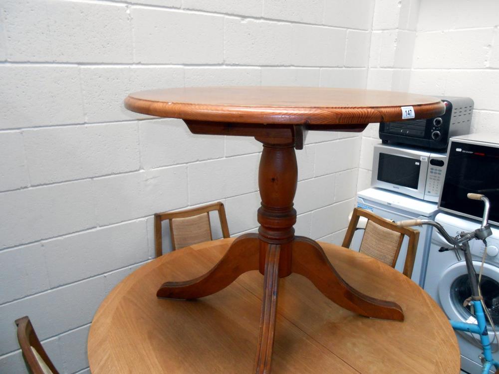 A solid dark pine round kitchen table on centre column with 4 legs