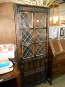 A dark oak cottage corner cupboard with leaded glass doors, height 169cm, width 66cm,