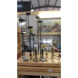 A wrought iron candleholder, a pair of brass candlesticks and other candlesticks.
