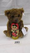A small Steiff teddy bear holding a Russian doll in good condition.