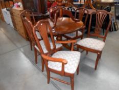 A dark wood stained round extending dining table and 6 chairs, diameter closed 109cm,