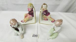 A pair of Quinrum porcelain figures of children with a pair of porcelain bookends of children,