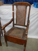 An oak chair commode the cane back.