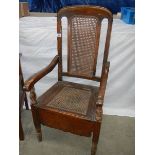 An oak chair commode the cane back.