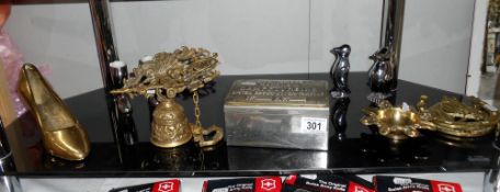 A shelf of metalware including brass bell, shoe, horse door knocker etc.