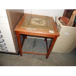 A small coffee table with tiled top depicting a bird (in need of a clean)