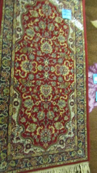 A red patterned rug, 137 x 68 cm.
