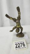 A small brass figure of a boy doing a hand stand on a marble base.