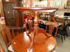 A dark pine round kitchen table on centre column tripod base, diameter 90cm,