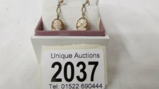 A pair of cameo ear pendants designed as profiles of young women in 9 carat gold.