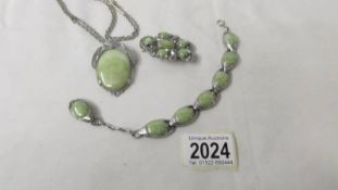 A matching necklace, pendant brooch and bracelet in a green colour set in white metal.