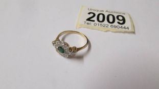 An 18ct gold floral ring with central emerald surrounded by diamonds, size M,