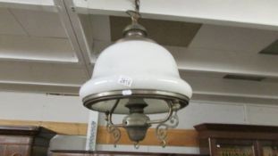 A brass hanging ceiling light with opaque glass shade.