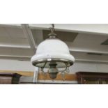 A brass hanging ceiling light with opaque glass shade.