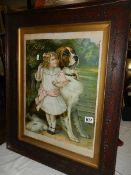A framed and glazed print of a girl with a St. Bernard dog.