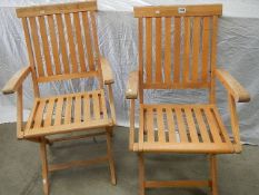 A pair of folding teak chairs.