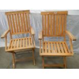 A pair of folding teak chairs.