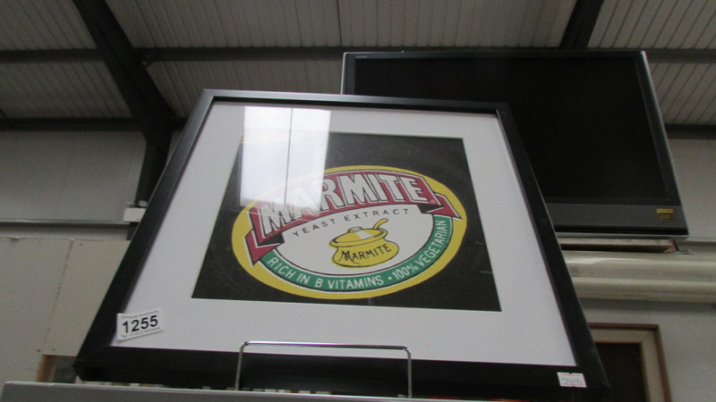 A framed and glazed Marmite advertisement.