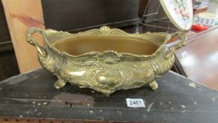 A decorative brass planter with plastic liner.
