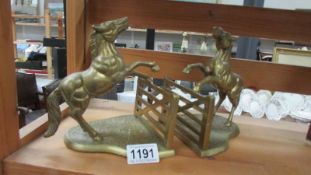 A pair of brass book stands being horses jumping fences.