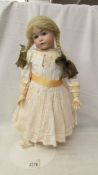 A porcelain doll with composition body in traditional costume. 50 cm.