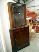 A dark oak corner cupboard with leaded glass door,