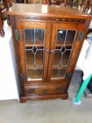 A dark oak leaded glazed cabinet with lift up lid,