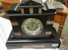An Edwardian black slate mantel clock with pink marble embelishments.