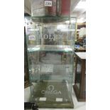 A glass display case - 'Rolex', 'Breiling', 'Omega'.