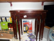 A dark wood stained nest of tables with red leather tops