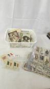 A box of vintage postcards, photographs, cigarette cards and cigarette silks.