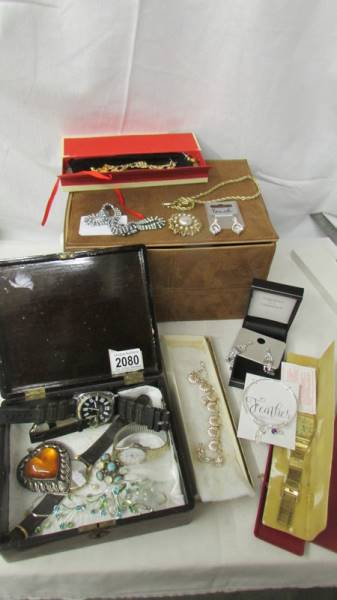 A faux suede box containing costume jewellery and watches.