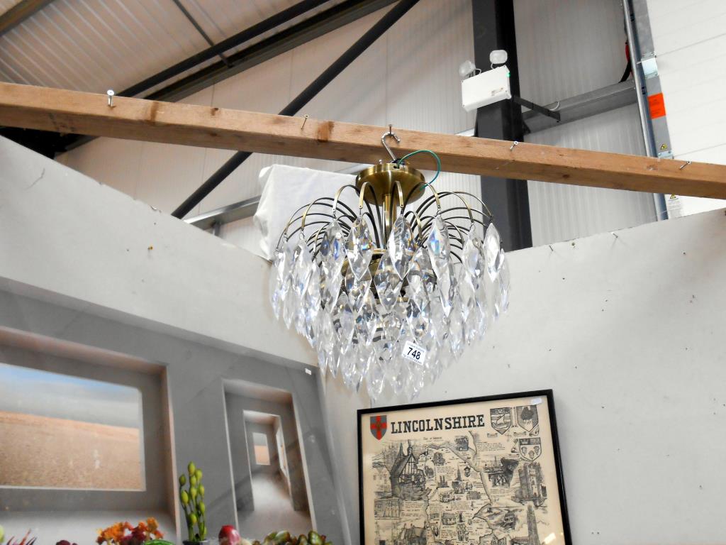A reproduction chandelier with antique brass frame and acrylic droppers