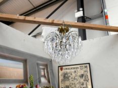 A reproduction chandelier with antique brass frame and acrylic droppers